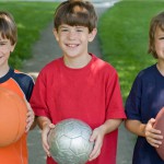 Three Boys Holding Sports Balls